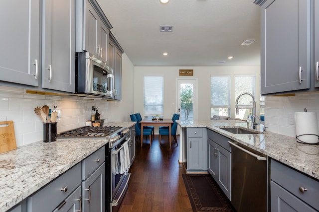 kitchen with a sink, dark wood-style flooring, stainless steel appliances, gray cabinets, and visible vents
