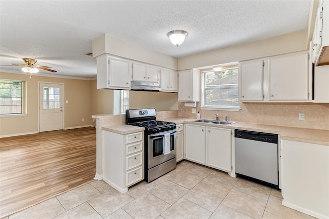 kitchen with a textured ceiling, stainless steel appliances, light countertops, and a sink