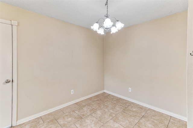spare room featuring baseboards, light tile patterned floors, and a notable chandelier