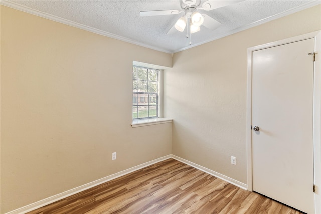 empty room featuring a ceiling fan, light wood-style flooring, baseboards, ornamental molding, and a textured ceiling