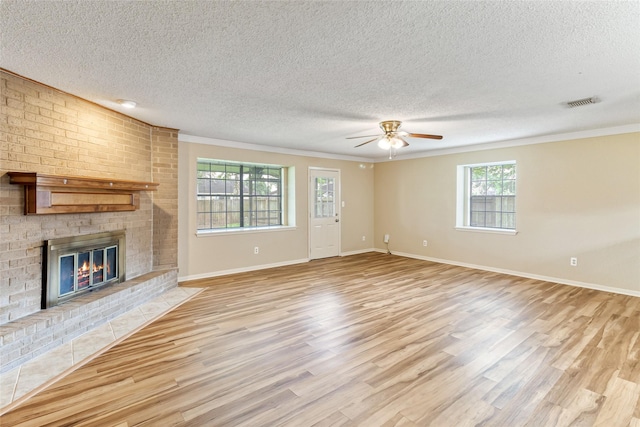 unfurnished living room with visible vents, light wood finished floors, a textured ceiling, and crown molding