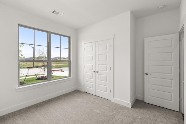 unfurnished bedroom with visible vents, baseboards, carpet flooring, and multiple windows
