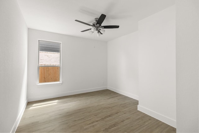 spare room with baseboards, wood finished floors, and ceiling fan