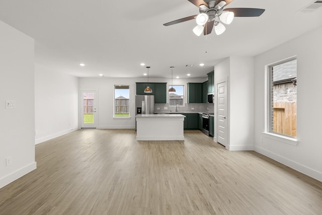 kitchen with stainless steel appliances, light countertops, backsplash, visible vents, and open floor plan