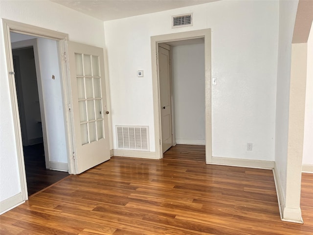 unfurnished room with wood finished floors, visible vents, and baseboards