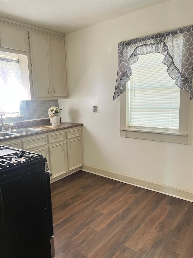 kitchen with a sink, black gas stove, dark wood-style flooring, and plenty of natural light