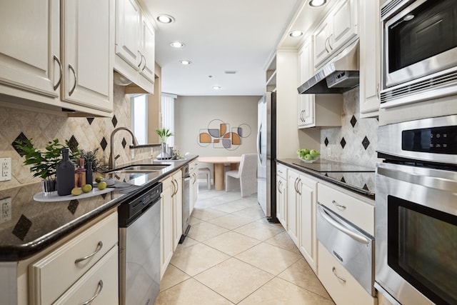 kitchen with light tile patterned floors, a sink, stainless steel appliances, under cabinet range hood, and a warming drawer