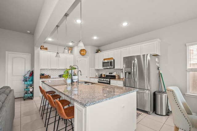 kitchen featuring a breakfast bar area, a sink, appliances with stainless steel finishes, and decorative backsplash