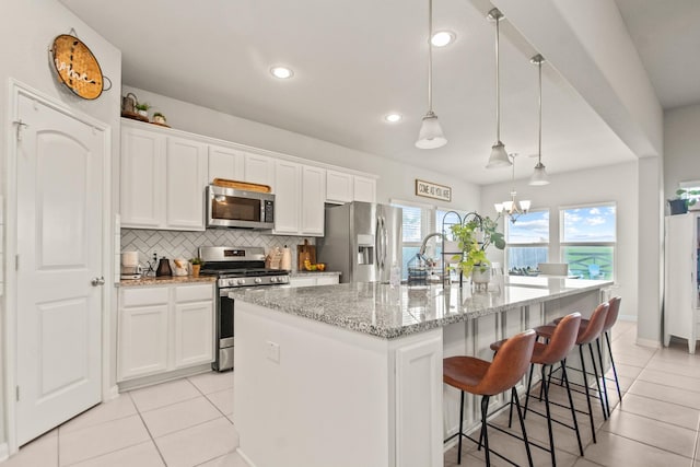 kitchen featuring light tile patterned floors, white cabinetry, a sink, appliances with stainless steel finishes, and backsplash