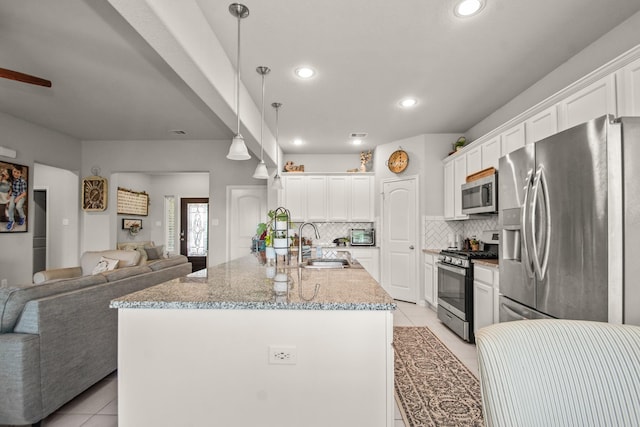 kitchen with a sink, light tile patterned floors, backsplash, appliances with stainless steel finishes, and open floor plan