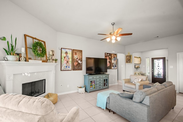 living room with visible vents, baseboards, light tile patterned flooring, a tiled fireplace, and a ceiling fan