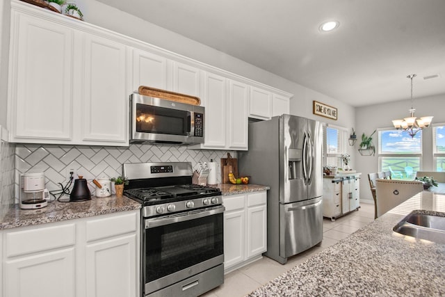 kitchen featuring an inviting chandelier, decorative backsplash, light tile patterned flooring, white cabinetry, and appliances with stainless steel finishes