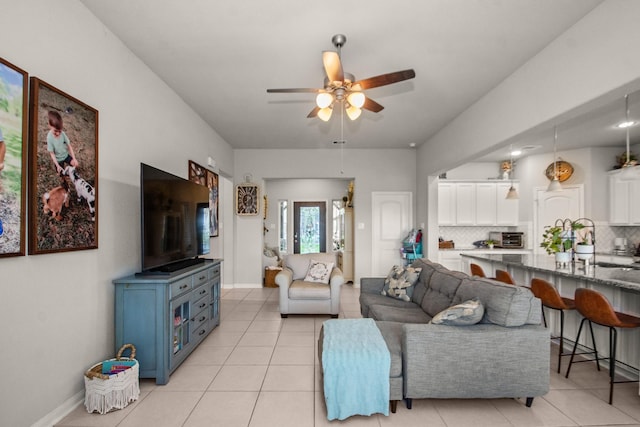 living area with baseboards, light tile patterned floors, and ceiling fan