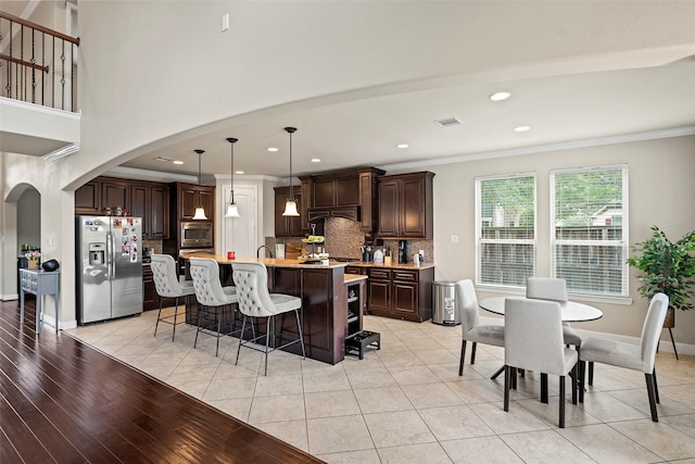 27803 Indigo Pointe Ln, Katy, TX 77494 - kitchen with stainless steel appliances, arched walkways, dark brown cabinetry, backsplash, and a kitchen breakfast bar