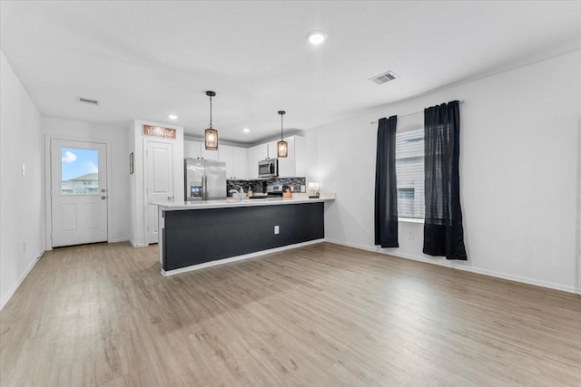 126 Spring Rose Dr, Magnolia, TX 77354 - kitchen with stainless steel appliances, a peninsula, light countertops, white cabinets, and light wood-type flooring