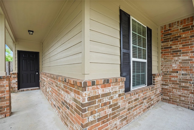 entrance to property with covered porch and brick siding