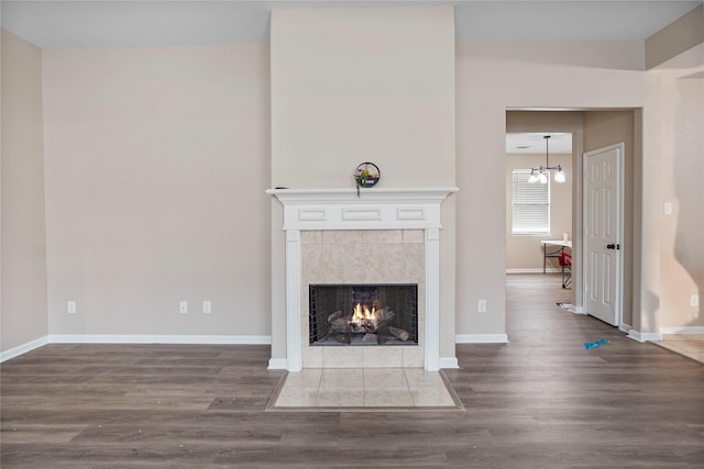 unfurnished living room featuring a tiled fireplace, baseboards, and wood finished floors