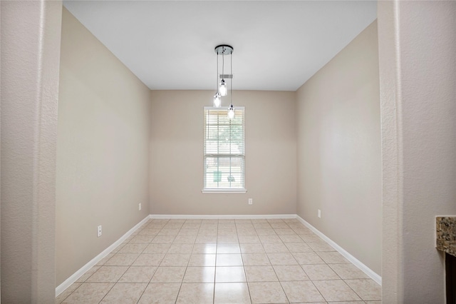 empty room with baseboards and light tile patterned floors