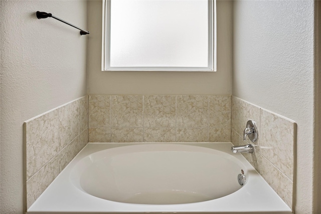 bathroom featuring a textured wall and a bath