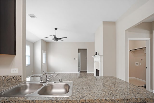 kitchen featuring a sink, a ceiling fan, baseboards, wood finished floors, and visible vents
