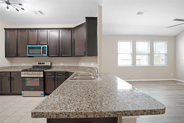 kitchen featuring visible vents, dark brown cabinetry, light stone countertops, a sink, and appliances with stainless steel finishes