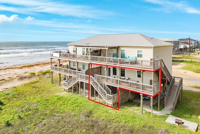 back of house featuring a view of the beach, stairway, and a deck with water view