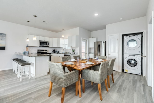 dining area with stacked washer / drying machine, visible vents, light wood-style floors, baseboards, and recessed lighting