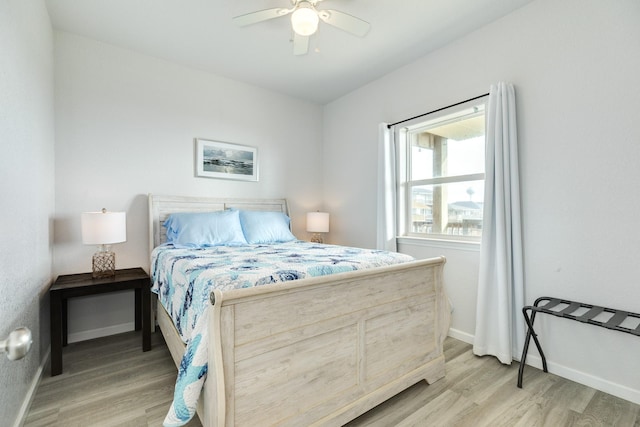 bedroom with a ceiling fan, light wood-style flooring, and baseboards