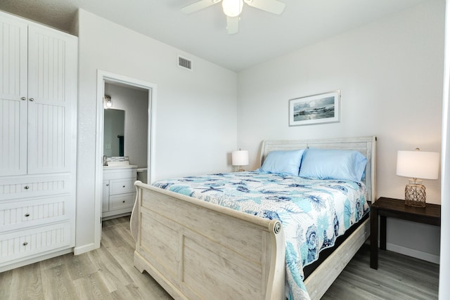 bedroom with connected bathroom, visible vents, light wood-style floors, baseboards, and a ceiling fan