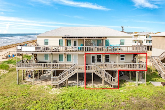 back of property featuring a lawn, a shingled roof, a deck with water view, and stairs