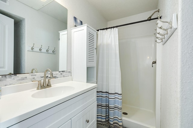 full bath featuring visible vents, a shower with shower curtain, a textured wall, and vanity