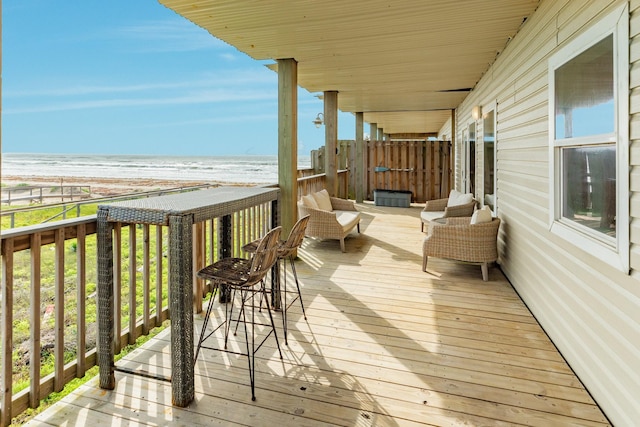 wooden terrace featuring a view of the beach and a water view