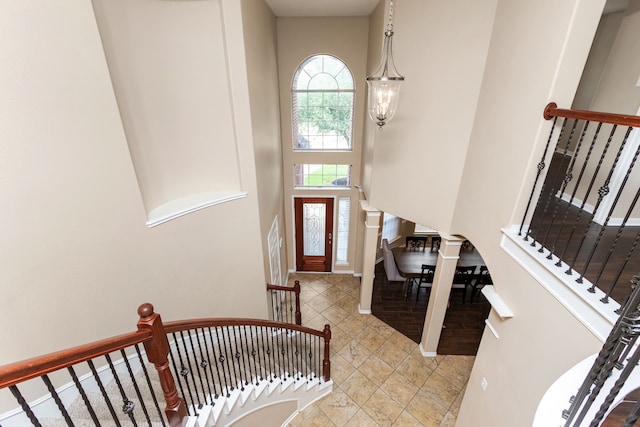 tiled entrance foyer featuring a towering ceiling and stairs