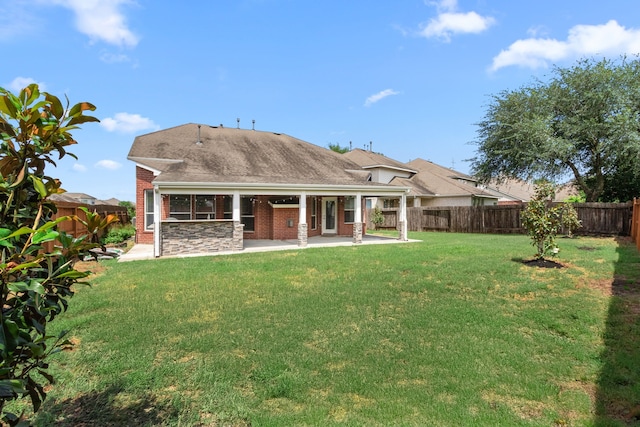 back of property featuring a lawn, brick siding, a fenced backyard, and a patio area