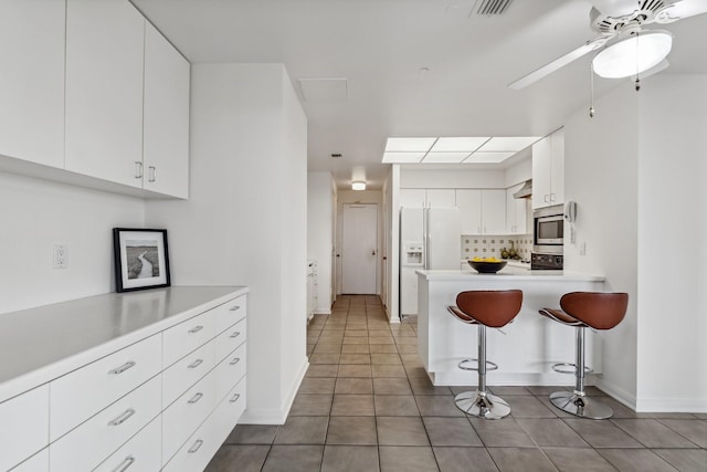101 Westcott St Unit 1402, Houston, TX 77007 - kitchen featuring stainless steel microwave, white fridge with ice dispenser, light countertops, and white cabinets