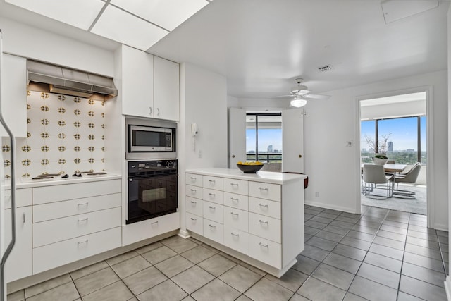 101 Westcott St Unit 1402, Houston, TX 77007 - kitchen featuring oven, stainless steel microwave, a peninsula, light tile patterned floors, and healthy amount of natural light