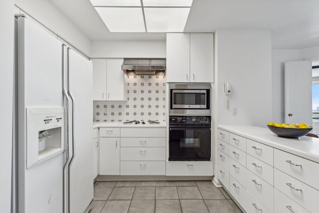 101 Westcott St Unit 1402, Houston, TX 77007 - kitchen featuring white appliances, wall chimney range hood, light countertops, white cabinets, and light tile patterned floors