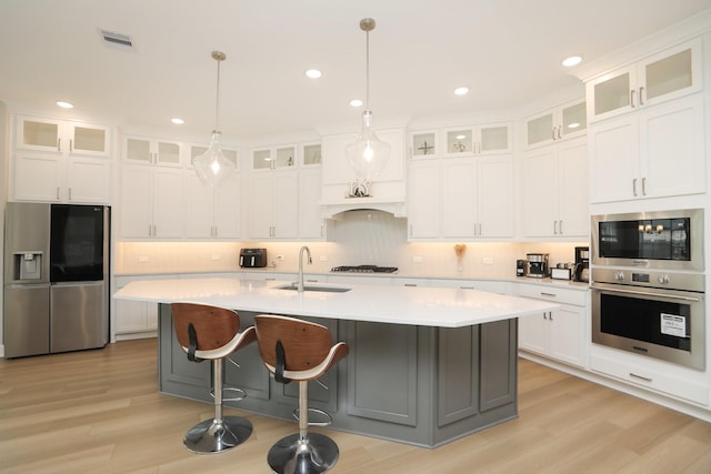 kitchen with a sink, visible vents, light wood-style flooring, light countertops, and appliances with stainless steel finishes