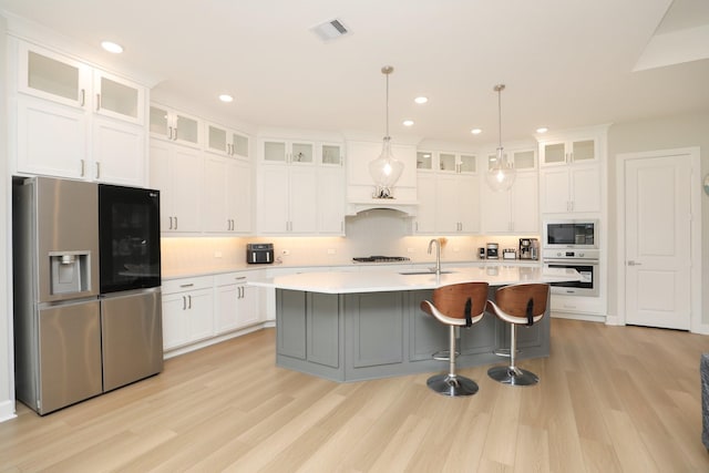 kitchen featuring light wood finished floors, a sink, stainless steel appliances, visible vents, and light countertops
