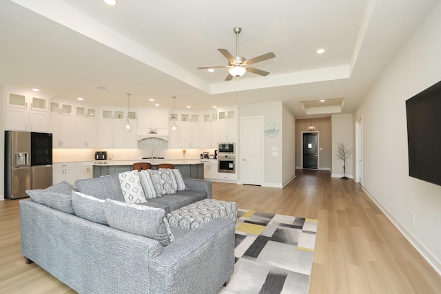 living area featuring recessed lighting, light wood-style floors, attic access, a raised ceiling, and a ceiling fan