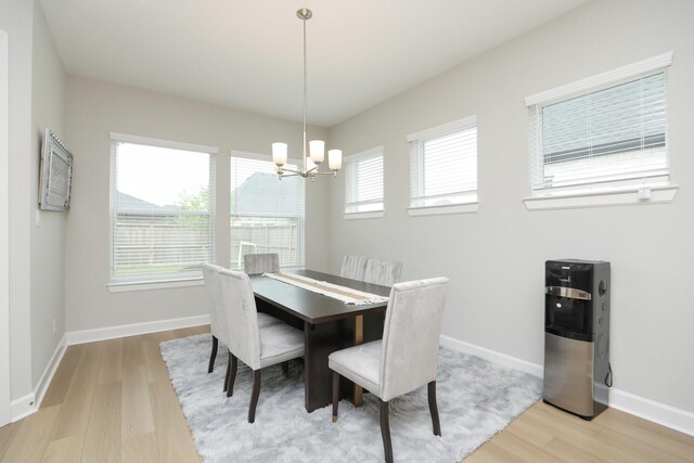 dining area with a chandelier, baseboards, and light wood finished floors