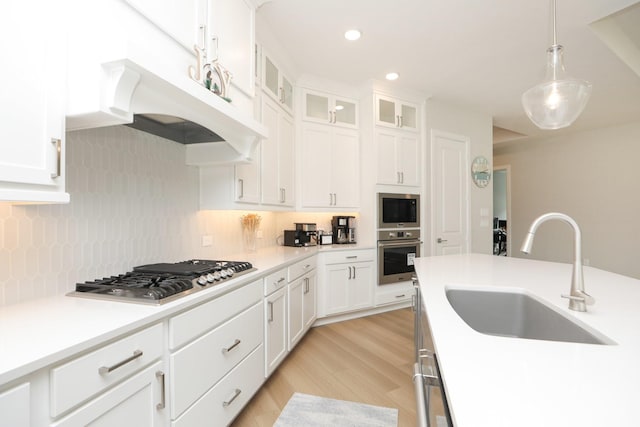 kitchen featuring appliances with stainless steel finishes, tasteful backsplash, white cabinets, and a sink