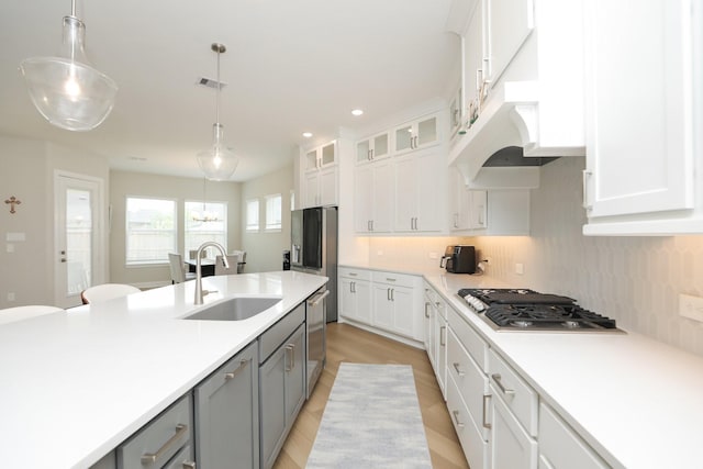 kitchen featuring a sink, stainless steel appliances, visible vents, white cabinetry, and hanging light fixtures