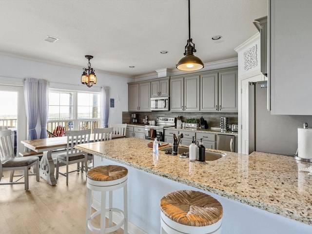 4138 Defender Ln, Galveston, TX 77554 - kitchen with light stone counters, a sink, visible vents, stainless steel appliances, and ornamental molding