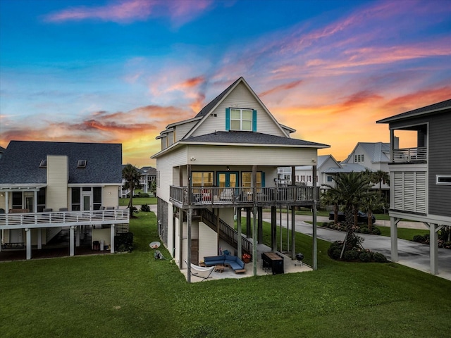 4138 Defender Ln, Galveston, TX 77554 - back of house at dusk featuring a lawn, a wooden deck, a patio, and roof with shingles