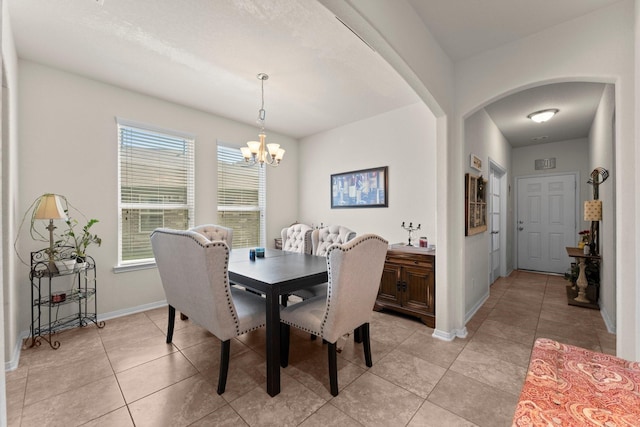 dining space featuring baseboards, light tile patterned floors, arched walkways, and an inviting chandelier