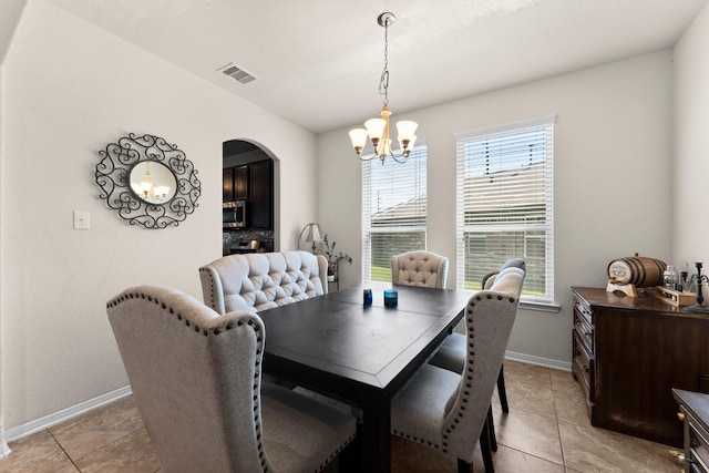 dining room featuring light tile patterned floors, visible vents, a chandelier, baseboards, and arched walkways