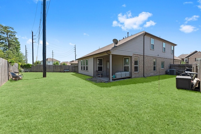 back of property with brick siding, a yard, a fenced backyard, and central AC unit