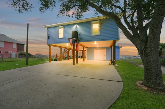 view of front of house featuring fence, a carport, concrete driveway, a lawn, and stairway