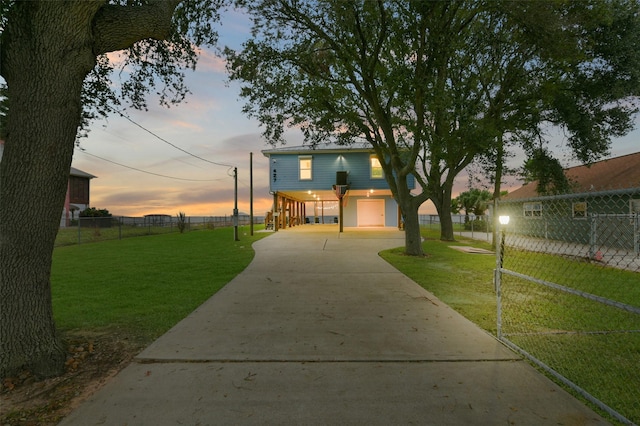 raised beach house with a carport, a yard, driveway, and fence
